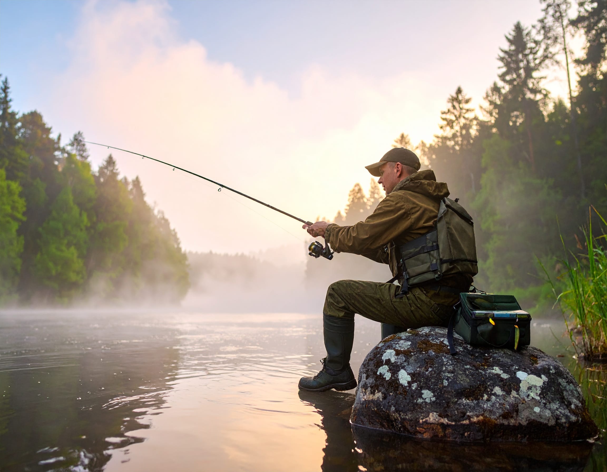 Zander angeln Tipps – Angler mit Spinnrute an Flussböschung bei Sonnenuntergang mit Zanderködern