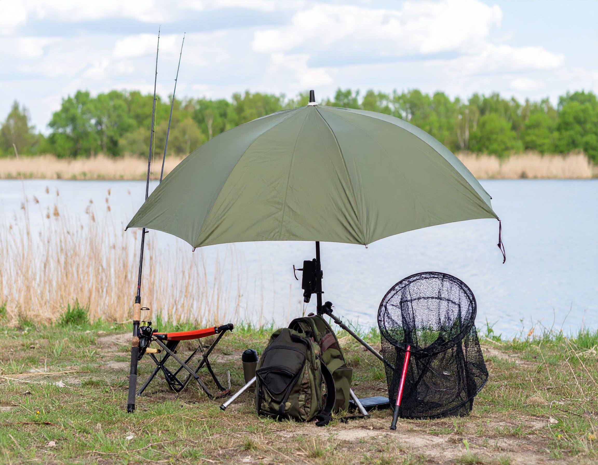 Angelschirm kaufen – robuster Schirm mit Windschutz und Angelausrüstung am Seeufer